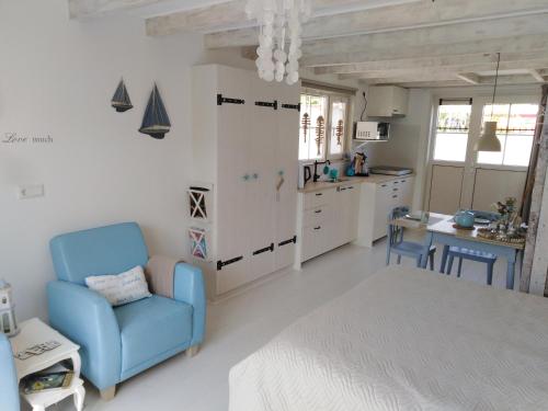 un soggiorno con sedia blu e una cucina di Tante Cher à la Mer - Zeeland a Biggekerke