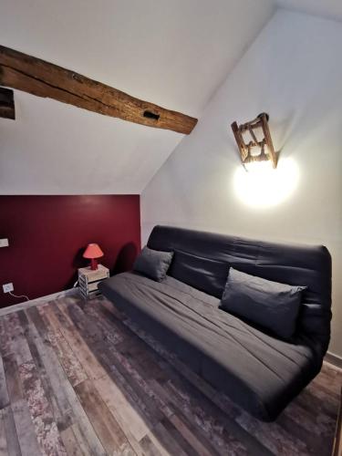 a bedroom with a black couch and a red wall at Gites les écuries Saserang in Mouilleron
