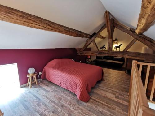 sypialnia z czerwonym łóżkiem na poddaszu w obiekcie Gites les écuries Saserang w mieście Mouilleron