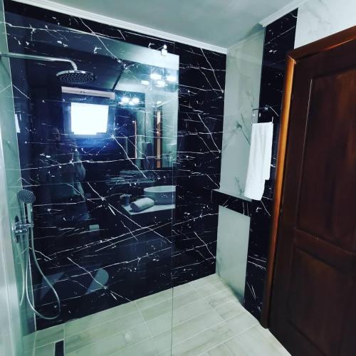 a bathroom with a black tiled shower with a glass door at Sidari Waterpark in Sidari