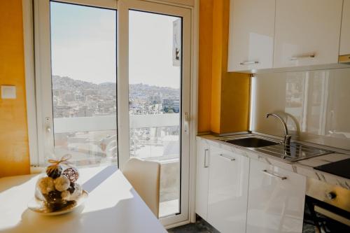 a kitchen with white cabinets and a large window at Aura Celestia in Kavála