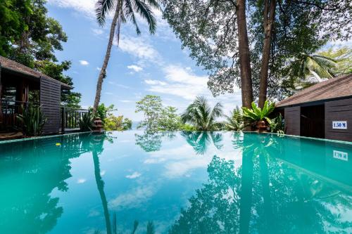 - une piscine en face d'une maison avec des palmiers dans l'établissement Baan Krating Khao Lak Resort - SHA plus, à Khao Lak