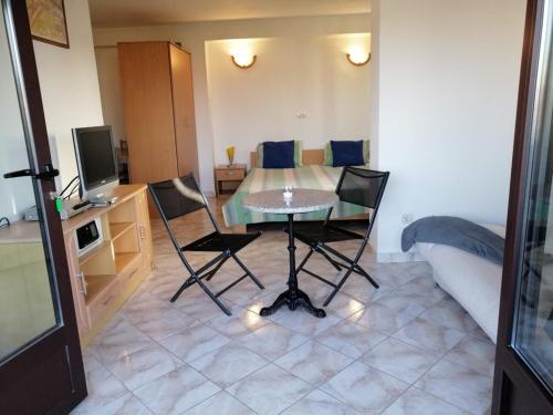 sala de estar con mesa, sillas y TV en Studio apartment in Funtana with balcony, air conditioning, WiFi, washing machine 4982-8, en Funtana