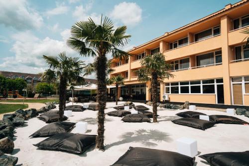 a courtyard with palm trees and sleeping bags in front of a building at Belenus Thermalhotel superior in Zalakaros