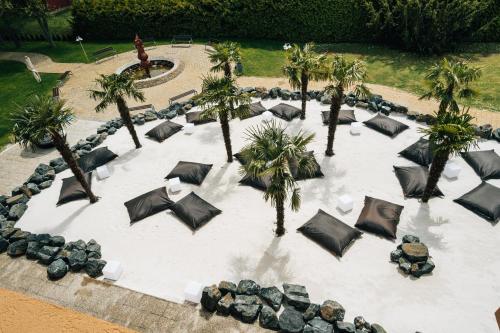 une cour avec des parasols noirs et des palmiers dans l'établissement Belenus Thermalhotel superior, à Zalakaros