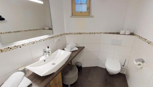 a white bathroom with a sink and a toilet at Appartements "Da Zillertaler und die Geigerin" in Mayrhofen