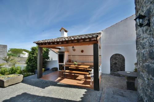 a patio with a wooden table and a roof at Charming green country house in Laseira