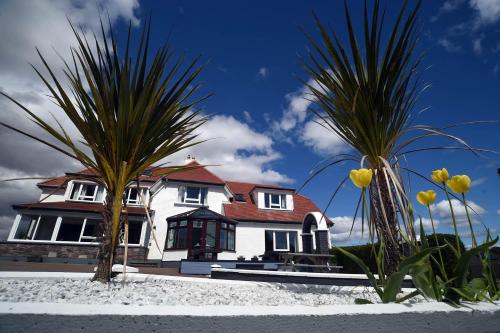 a white house with palm trees in front of it at Portree Guest House in Portree