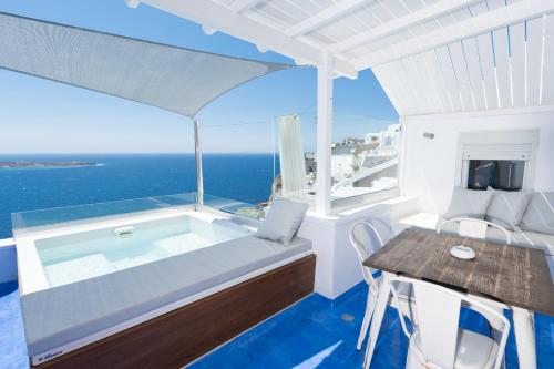 a jacuzzi tub on a balcony with the ocean at Hyperion Oia Suites in Oia