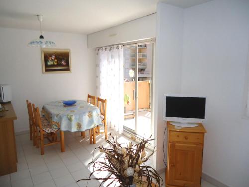 uma sala de estar com televisão e uma mesa com mesa; em Appartement climatisé avec grande terrasse plein sud em Cavalaire-sur-Mer