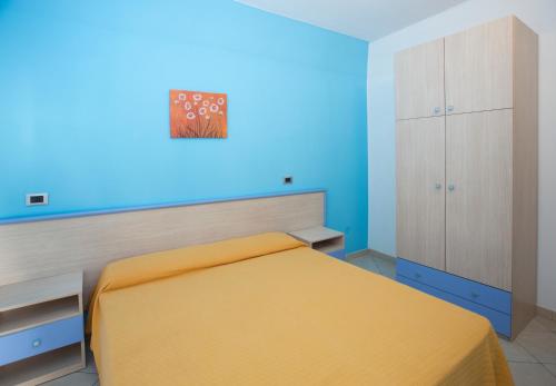 a bedroom with a yellow bed and a blue wall at Terra del Sole in Favignana