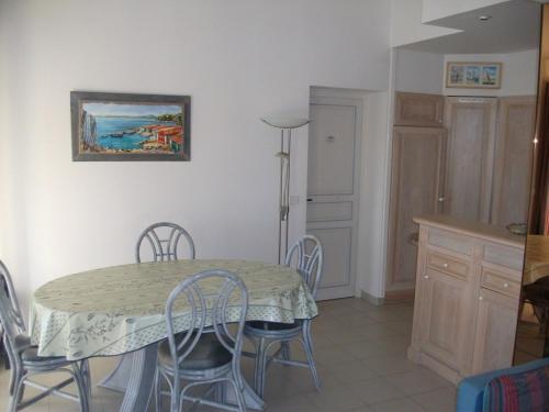 une salle à manger avec une table et des chaises et une cuisine dans l'établissement Bel appartement climatisé - Résidence avec piscine, à Cavalaire-sur-Mer