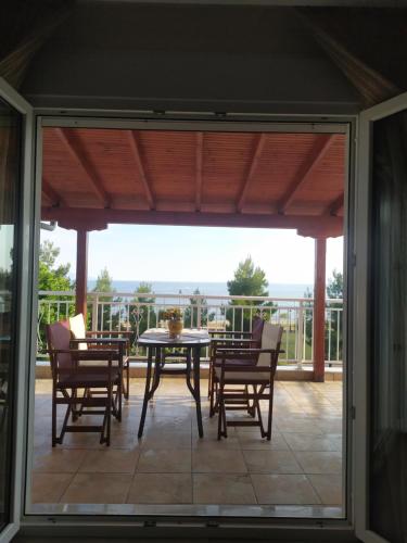 een afgeschermde veranda met een tafel en stoelen bij Aegean View Apartment in Kavala