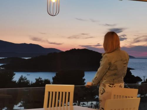 a woman standing on a balcony watching the sunset at Hotel Queen Margaret Seaside in Ksamil