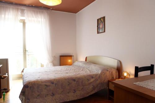 1 dormitorio con cama, mesa y ventana en Rooms Torcello - with shared bathroom, en Portorož