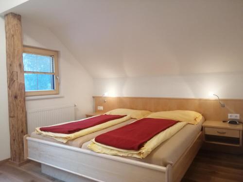 Ferienhof Gindl und Gästehaus Gindl في توبليتز: غرفة نوم بسريرين وبطانيات حمراء وصفراء