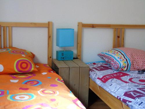 una camera con 2 letti e una lampada blu su un comodino di ORELLE VALLEE DE LA MAURIENNE a Orelle