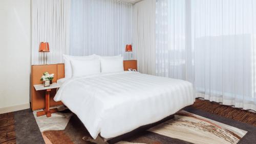 a large white bed in a room with a window at Lotte Hotel Seattle in Seattle