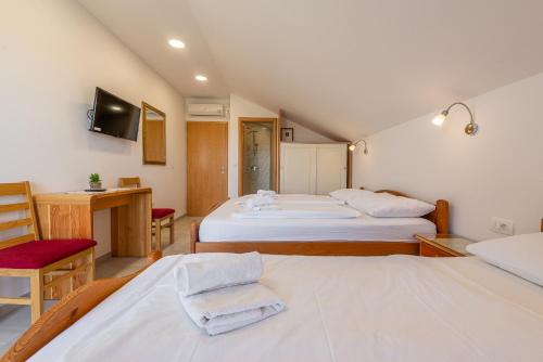 a bedroom with two beds and a desk and a tv at Bed & Breakfast Maki in Biograd na Moru