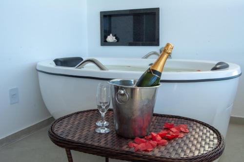 a bottle of champagne in a bucket next to a bath tub at Pousada Pénareia in Morro de São Paulo