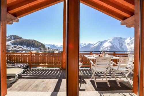 a deck with a table and chairs and a view of the mountains at Casa Arturo Penthouse in Riederalp