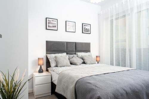a white bedroom with a large bed and a window at Apartament SEA HOLIDAY in Kołobrzeg