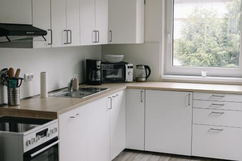 a kitchen with white cabinets and a window at Apartmány u kostela in Lipova Lazne
