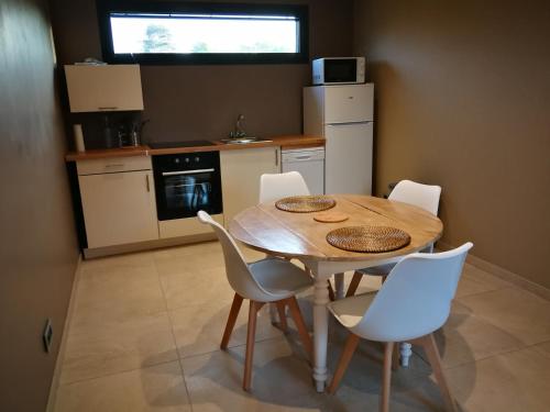 uma cozinha com uma mesa de madeira e cadeiras brancas em Terre des marais em Marchésieux