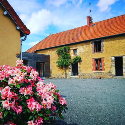 a building with pink flowers in front of it at Terre des marais in Marchésieux