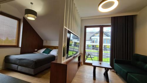 ein Schlafzimmer mit einem Bett und einem Sofa sowie einem Balkon in der Unterkunft APARTAMENTY SKORUPKI-Mazury Mikołajki in Skorupki