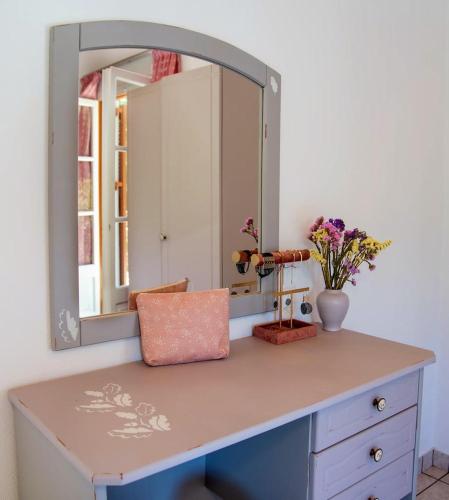 a dressing table with a mirror and flowers on it at LIvadi Studios with Pool in Lákka