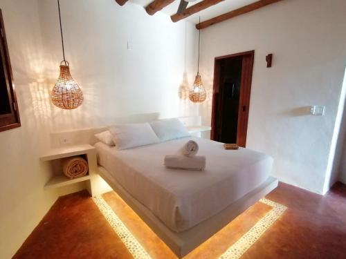 een slaapkamer met een wit bed met een handdoek erop bij Casa Mech in Holbox Island