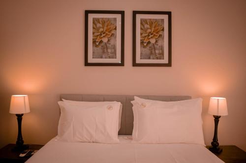 a bedroom with two pictures above a bed with white pillows at Terra Guest House in Maputo