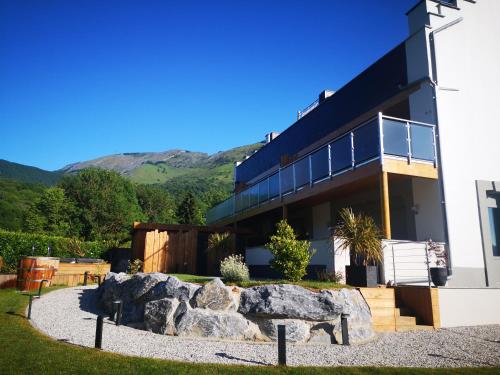 a black building with a rock garden in front of it at L'Argalyde Esprit Pyrénées Wellness & Cycling in Ayzac-Ost