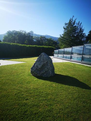 a rock sitting on the grass in front of a building at L'Argalyde Esprit Pyrénées Wellness & Cycling in Ayzac-Ost