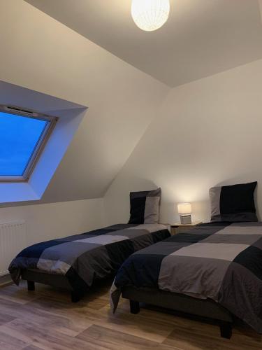 deux lits dans une chambre avec une fenêtre dans l'établissement Maison neuve à 350m de la plage La casa Sovaïna, à Cléder