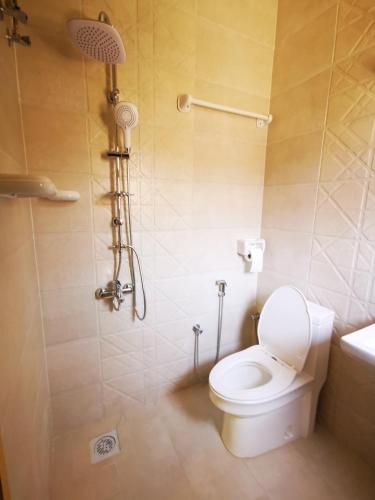 a bathroom with a white toilet and a shower at Al Hamra Guest House in Al Ḩamrāʼ