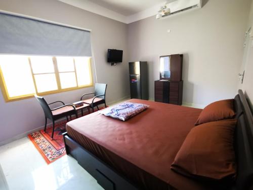 a bedroom with a bed and two chairs and a window at Al Hamra Guest House in Al Ḩamrāʼ