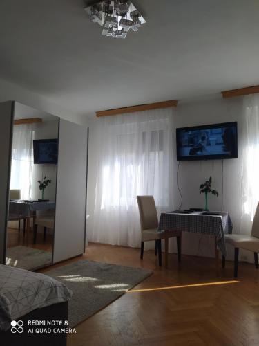 un soggiorno con tavolo, sedie e TV di Dóm Tér Apartman a Szeged