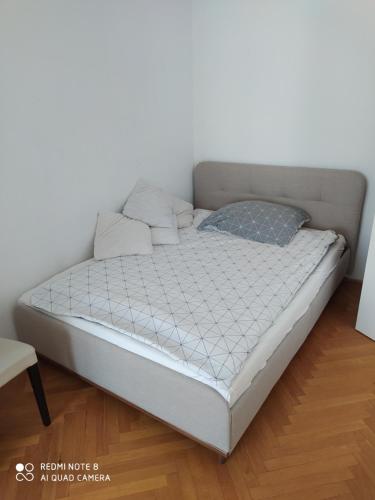 a bed in a room with a white wall at Dóm Tér Apartman in Szeged