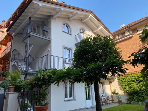 a white building with a tree in front of it at Garden Lodge in Stresa