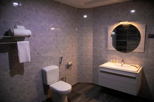 a bathroom with a toilet and a sink and a mirror at Hotel La Casa Cielo in Cotonou