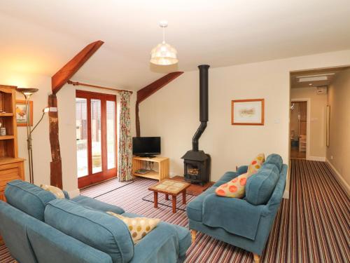 a living room with two blue chairs and a fireplace at The Shippen in Northleigh
