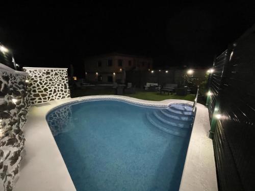 a swimming pool at night with lights around it at Vistamar La Caleta in La Caleta
