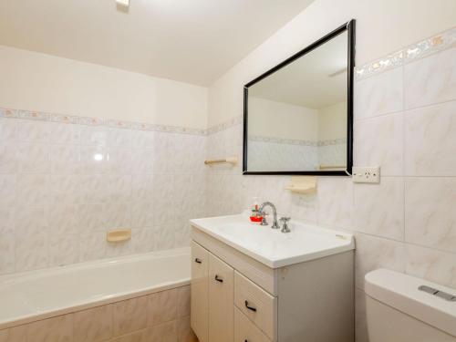 La salle de bains blanche est pourvue d'un lavabo et d'un miroir. dans l'établissement Ebbtide 6, à Forster