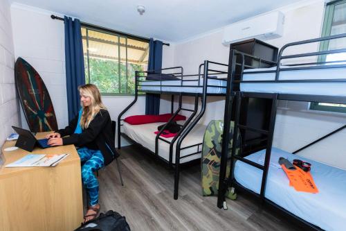 a woman sitting at a desk in a room with bunk beds at Manta Lodge YHA & Scuba Centre in Point Lookout
