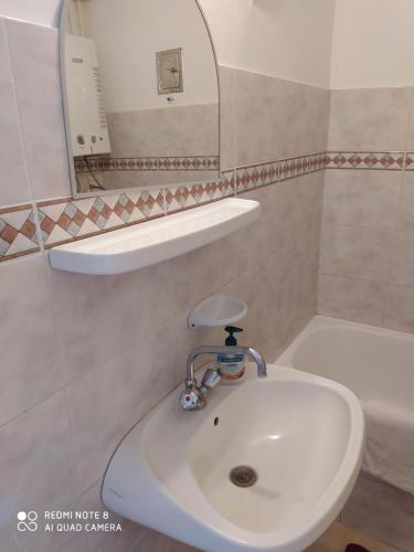 a bathroom with a sink and a mirror and a tub at Dóm Tér Apartman in Szeged
