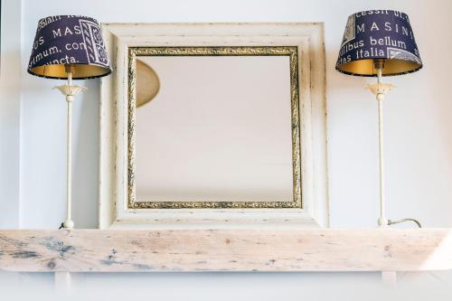 a mirror on top of a shelf with two lamps at Mylos Studios in Alkmaar