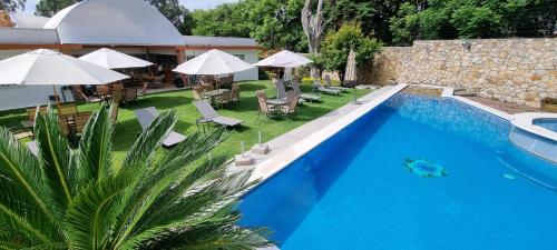 una piscina con sillas y sombrillas junto a una casa en Victoria Hotel y Spa, en Ixtapan de la Sal