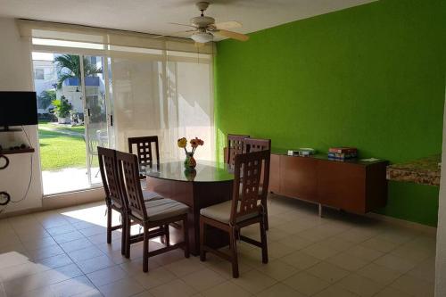 a dining room with a table and chairs and a green wall at Casa en Acapulco Diamante in Acapulco